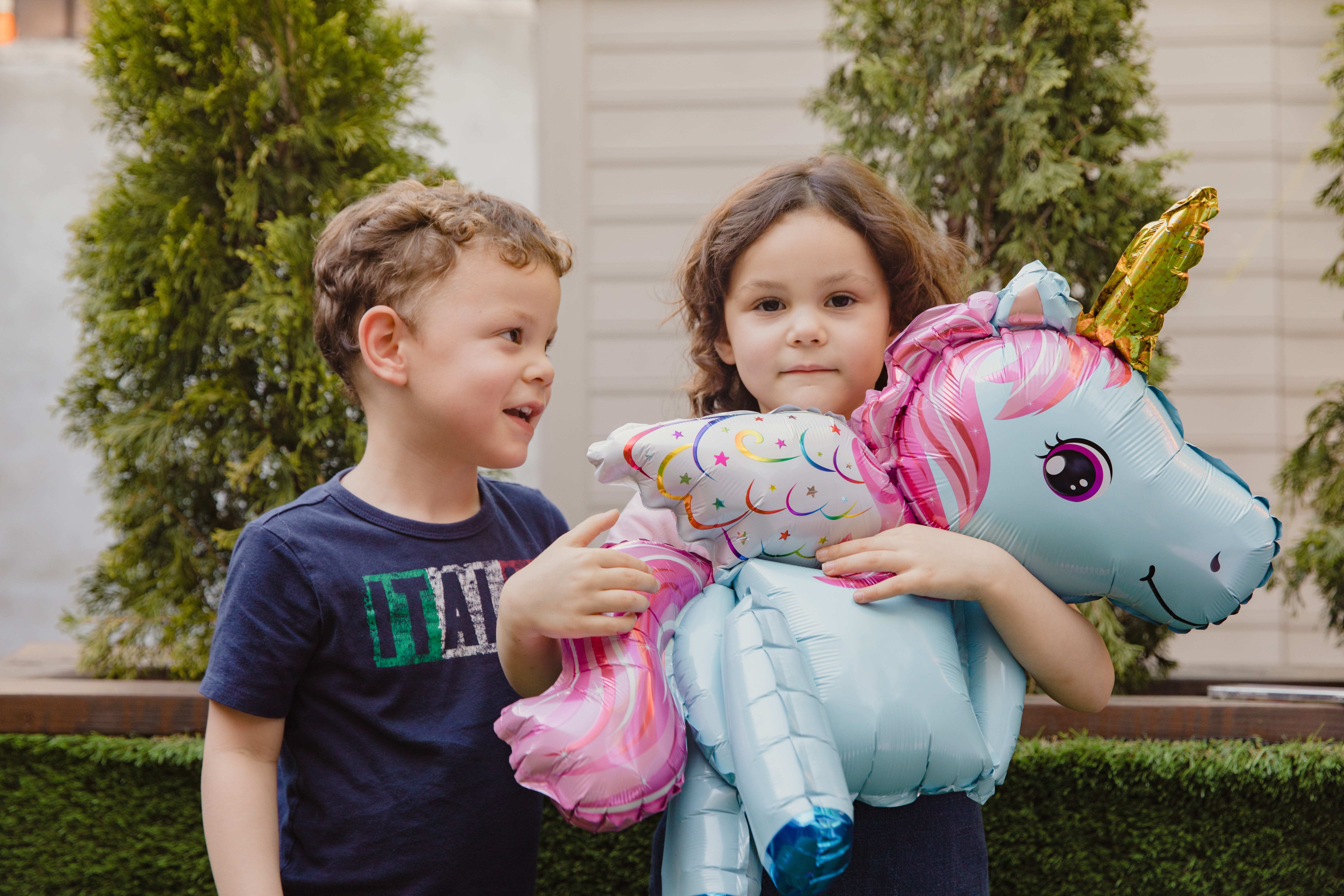 Little boy and girl holding a unicorn balloon