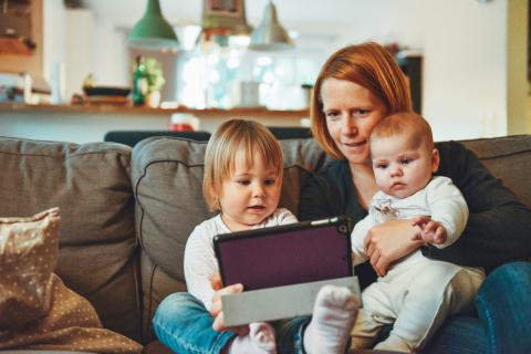 parent/guardian looking at tablet with children