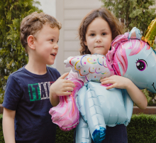 Brother & sister holding unicorn balloon